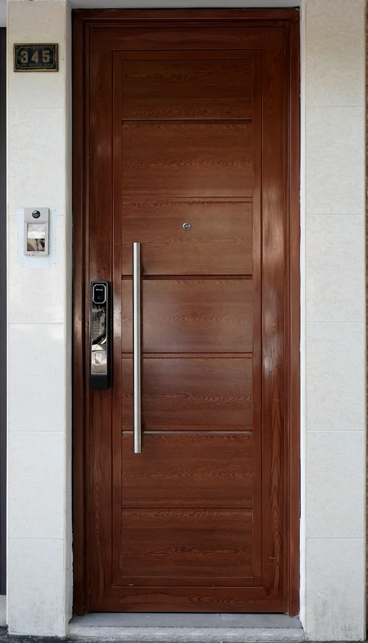 Puerta moderna de madera con franjas negras y jalador vertical instalada en residencia.