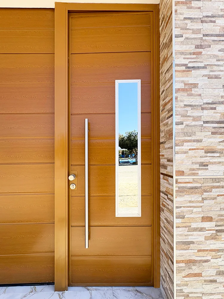 Puerta principal de paneles importados con acabado cedro dorado instalada en residencia.