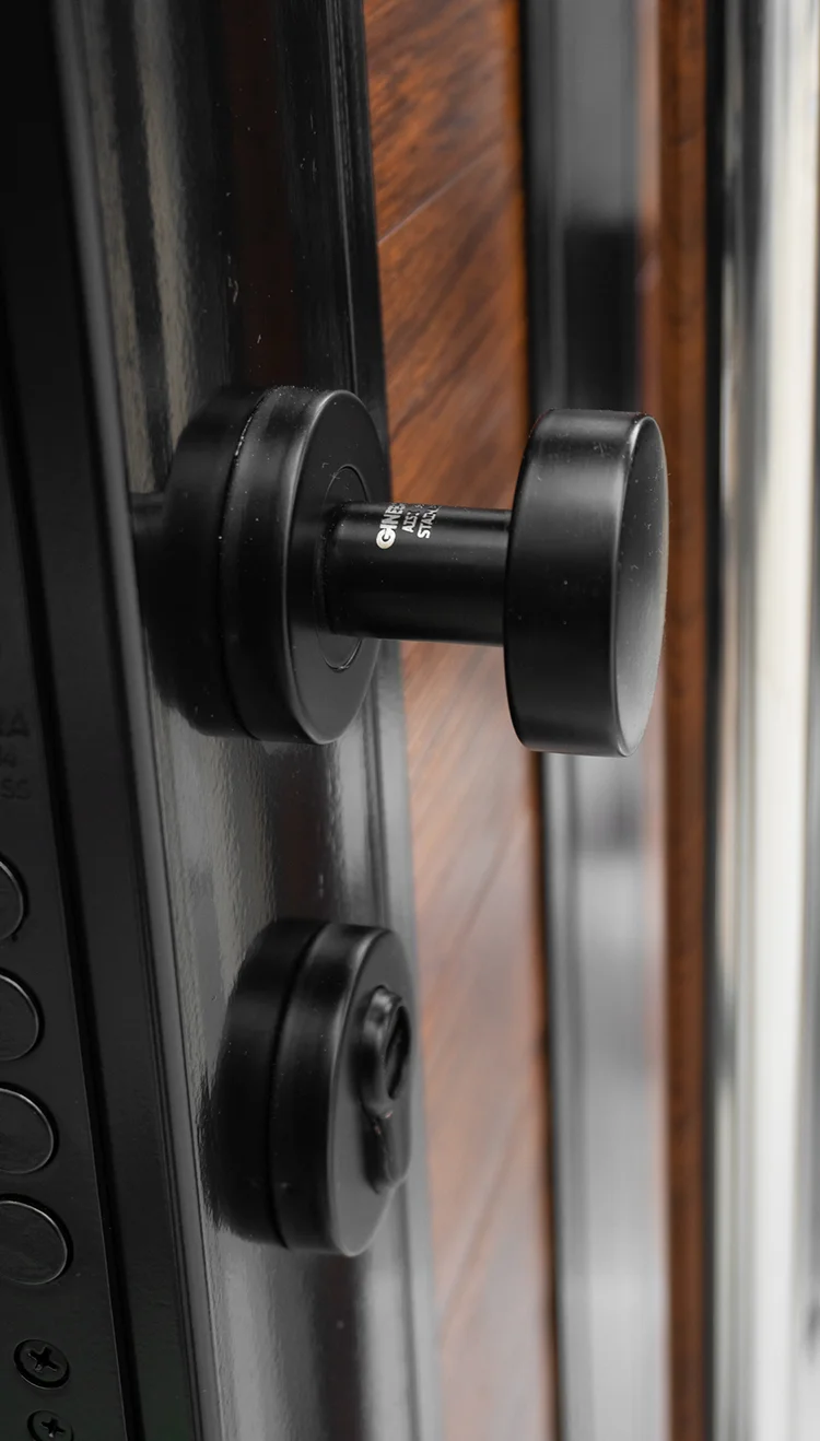 Primer plano de una cerradura de alta seguridad con pomo en una puerta con marco de acero negro.