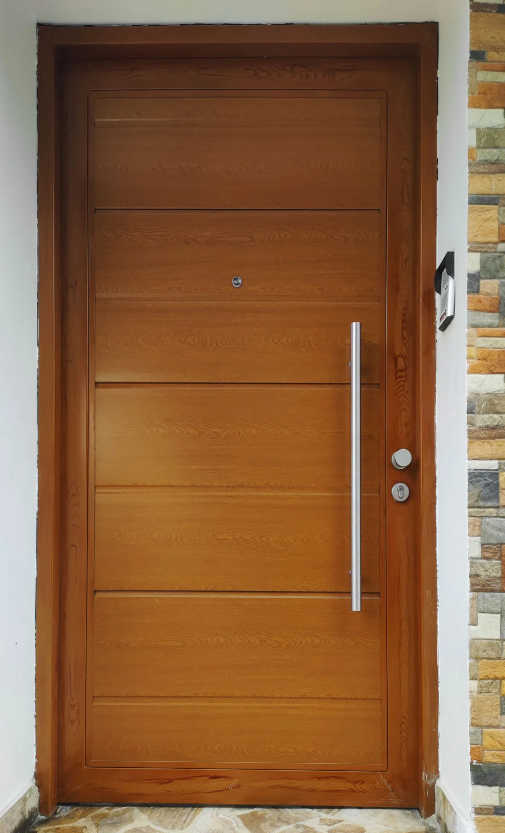 Puerta de ingreso estilo madera con manillón de acero.